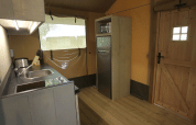 Kitchen area in Glamping Haritza safari tent at Camping Etxarri, Spain, featuring a sink, fridge, and microwave.