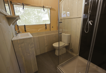 Bagno in una tenda safari presso Glamping Haritza, Camping Etxarri in Spagna, con doccia, WC e lavandino.