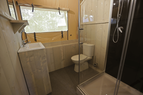 Bagno in una tenda safari presso Glamping Haritza, Camping Etxarri in Spagna, con doccia, WC e lavandino.