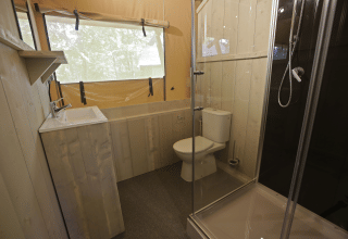 Bagno in una tenda safari presso Glamping Haritza, Camping Etxarri in Spagna, con doccia, WC e lavandino.