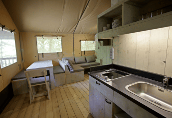Interior of a safari glamping tent Glamping Haritza at Camping Etxarri in Spain, showing kitchen and seating area.