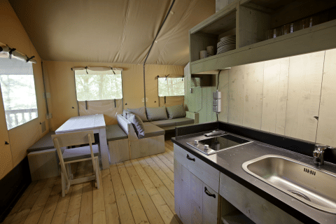Interno di una tenda safari Glamping Haritza presso Camping Etxarri in Spagna, con cucina e zona soggiorno.