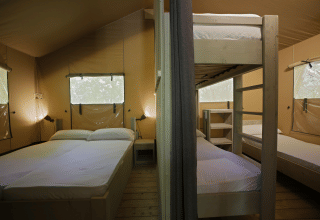 Interno di una tenda safari al Glamping Haritza, Camping Etxarri in Spagna, con letto matrimoniale e letti a castello.