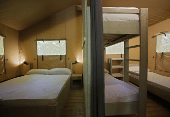 Interno di una tenda safari al Glamping Haritza, Camping Etxarri in Spagna, con letto matrimoniale e letti a castello.