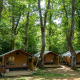 Tre safari telte i Glamping Jare midt i en skov, omgivet af grønne træer og naturligt lys.