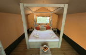 Interior view of a cozy bed in the safari tent Glamping Jare at Camping Etxarri, Spain, with wooden decor.