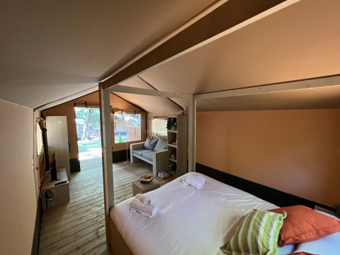 Interno di una tenda safari di lusso a Glamping Jare, Camping Etxarri, Spagna, con letto e salotto accoglienti.