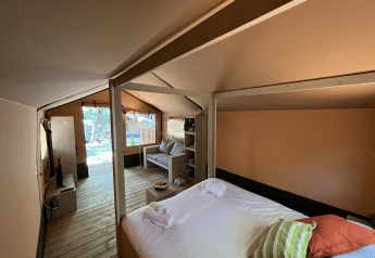 Interno di una tenda safari di lusso a Glamping Jare, Camping Etxarri, Spagna, con letto e salotto accoglienti.