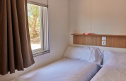 Foto de una sencilla habitación de cabina con dos camas individuales, ventana y repisa de madera arriba.