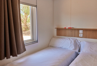 Foto de una sencilla habitación de cabina con dos camas individuales, ventana y repisa de madera arriba.