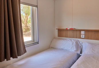 Foto de una sencilla habitación de cabina con dos camas individuales, ventana y repisa de madera arriba.