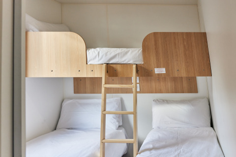 Praktisches Kabinenzimmer mit drei Betten: zwei Einzelbetten unten und ein Hochbett mit Leiter.