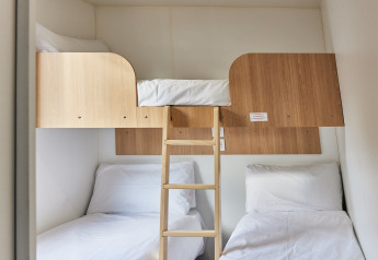 Praktisches Kabinenzimmer mit drei Betten: zwei Einzelbetten unten und ein Hochbett mit Leiter.