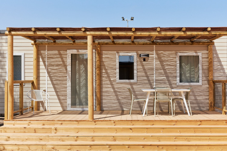 Holzterrasse mit Tisch und Stühlen vor dem Bungalow Premium Agave, teilweise überdacht, sonnig.
