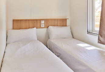 Dos camas individuales con sábanas blancas en una habitación luminosa, Bungalow Premium Agave, TAIGA Almeria Playa, España.