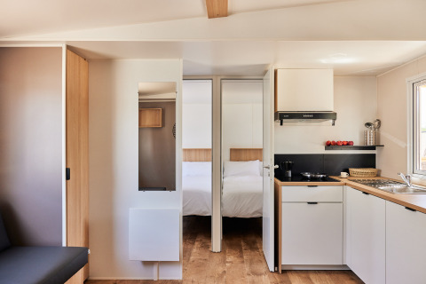 Interior moderno de cocina y dormitorio en Bungalow Premium Agave de TAIGA Almeria Playa, España.