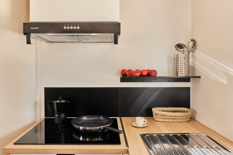 Moderna cocina pequeña en Bungalow Premium Agave, TAIGA Almeria Playa, con vitrocerámica, sartén y frutas.