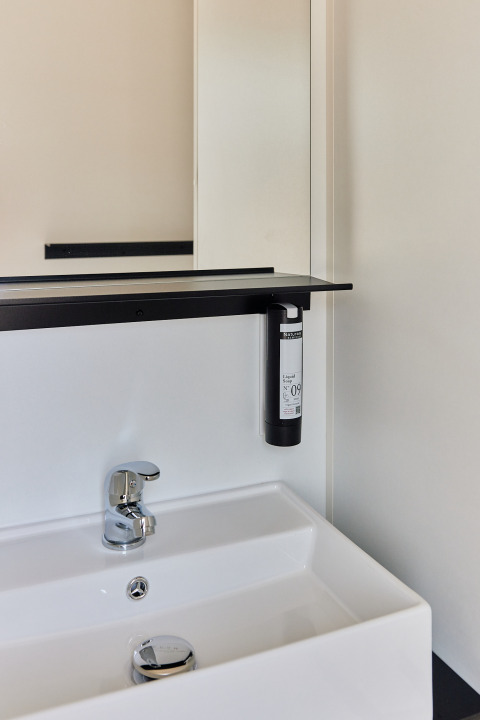 Moderno lavabo de baño con espejo y dispensador de jabón en Bungalow Premium Agave, TAIGA Almeria Playa, España.