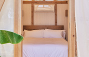Dormitorio en tienda safari con marco de madera, cama doble y aire acondicionado en TAIGA Almeria Playa, España.