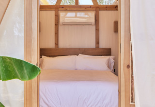 Camera in tenda safari con struttura in legno, letto matrimoniale e aria condizionata a TAIGA Almeria Playa, Spagna.