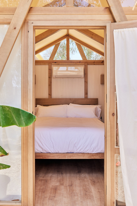 Dormitorio en tienda safari con marco de madera, cama doble y aire acondicionado en TAIGA Almeria Playa, España.