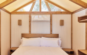 Interior of a safari glamping tent featuring a cozy bed and wood accents at TAIGA Almeria Playa in Spain.