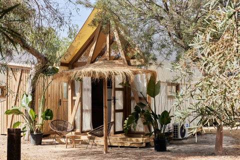 Foto des Glamping Tent Almanzora, ein Safarizelt mit Holzrahmen und gemütlicher Sitzgelegenheit draußen.
