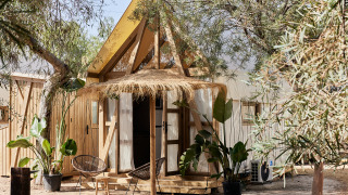 Foto des Glamping Tent Almanzora, ein Safarizelt mit Holzrahmen und gemütlicher Sitzgelegenheit draußen.
