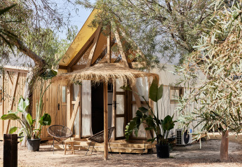 Foto des Glamping Tent Almanzora, ein Safarizelt mit Holzrahmen und gemütlicher Sitzgelegenheit draußen.