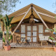 Tienda de glamping tipo safari Alhamilla con terraza de madera, asientos exteriores y plantas tropicales.