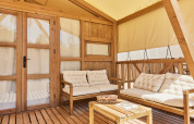 Udendørs loungeområde i safari glamping telt Alhamilla med træmøbler og bløde hynder, TAIGA Almeria Playa.