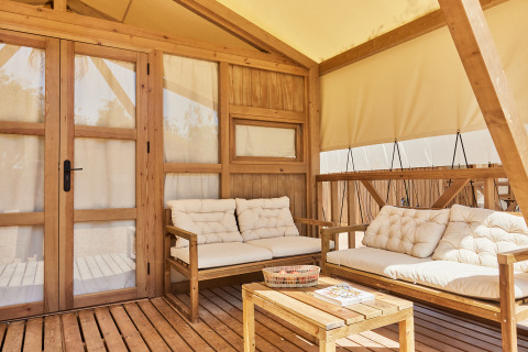 Area lounge esterna della tenda glamping Alhamilla a TAIGA Almeria Playa, Spagna, con arredi in legno.