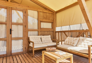 Area lounge esterna della tenda glamping Alhamilla a TAIGA Almeria Playa, Spagna, con arredi in legno.