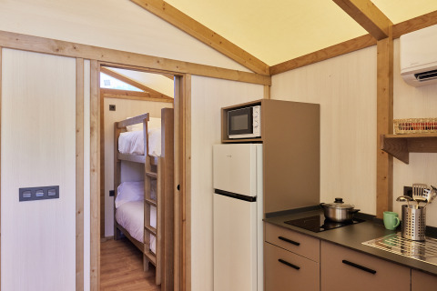 Vista interior de la Glamping Tent Alhamilla con cocina, literas y comodidades modernas en España.