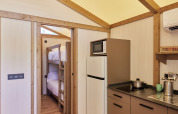 Vista interior de la Glamping Tent Alhamilla con cocina, literas y comodidades modernas en España.