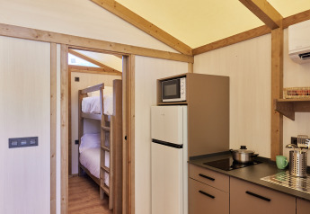 Vista interior de la Glamping Tent Alhamilla con cocina, literas y comodidades modernas en España.