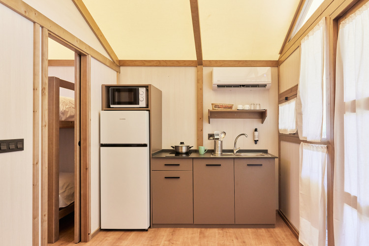 Cozy kitchenette inside Glamping Tent Alhamilla at TAIGA Almeria Playa in Spain, with fridge and microwave.