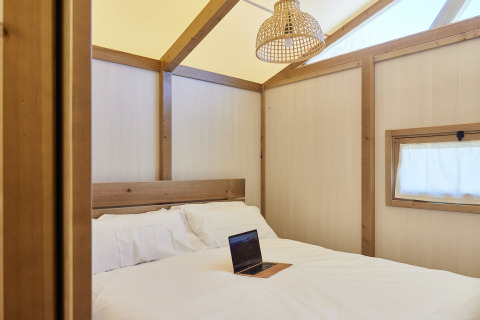 Schlafzimmer im Glamping Tent Alhamilla, TAIGA Almeria Playa, Spanien mit Bett, Laptop und natürlichem Licht.