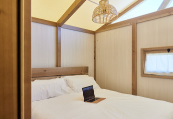 Schlafzimmer im Glamping Tent Alhamilla, TAIGA Almeria Playa, Spanien mit Bett, Laptop und natürlichem Licht.