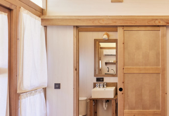 Binnenzicht van Glamping Tent Alhamilla met houtaccenten en badkamer in TAIGA Almeria Playa, Spanje.