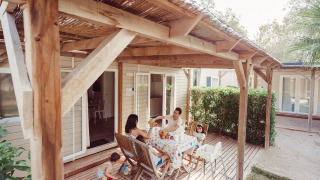 Familia desayunando al aire libre en Bungalow Confort Baconé, compartiendo momentos en la terraza.