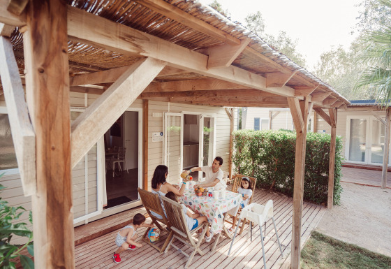 Familie frühstückt auf der Veranda des Bungalow Confort Baconé, umgeben von Natur und Gemütlichkeit.