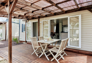 Terrasse mit Holzmöbeln vor dem Bungalow Confort Baconé im TAIGA Delta de l'Ebre in Spanien.