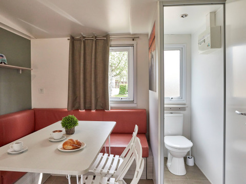 Binnenzicht van Bungalow Confort Baconé in TAIGA Delta de l'Ebre met eetruimte en zicht op badkamer.