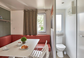 Indvendig udsigt over Bungalow Confort Baconé på TAIGA Delta de l'Ebre med spisebord og badværelse.