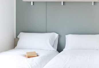 Deux lits simples aux draps blancs au Bungalow Confort Baconé, TAIGA Delta de l'Ebre, Espagne.