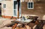 Mesa de madera al aire libre con café y fruta frente a una cabaña en TAIGA Delta de l'Ebre, España.