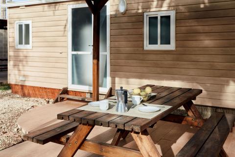 Table de pique-nique avec café et fruits devant un bungalow à TAIGA Delta de l'Ebre, Espagne.