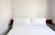 Dormitorio minimalista en Bungalow Essential Golero, TAIGA Delta de l'Ebre, España, con ropa de cama blanca.