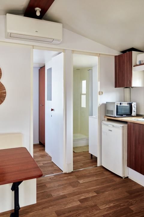 Vue intérieure du Bungalow Essential Golero à TAIGA Delta de l'Ebre, Espagne, montrant cuisine et salle de bain.